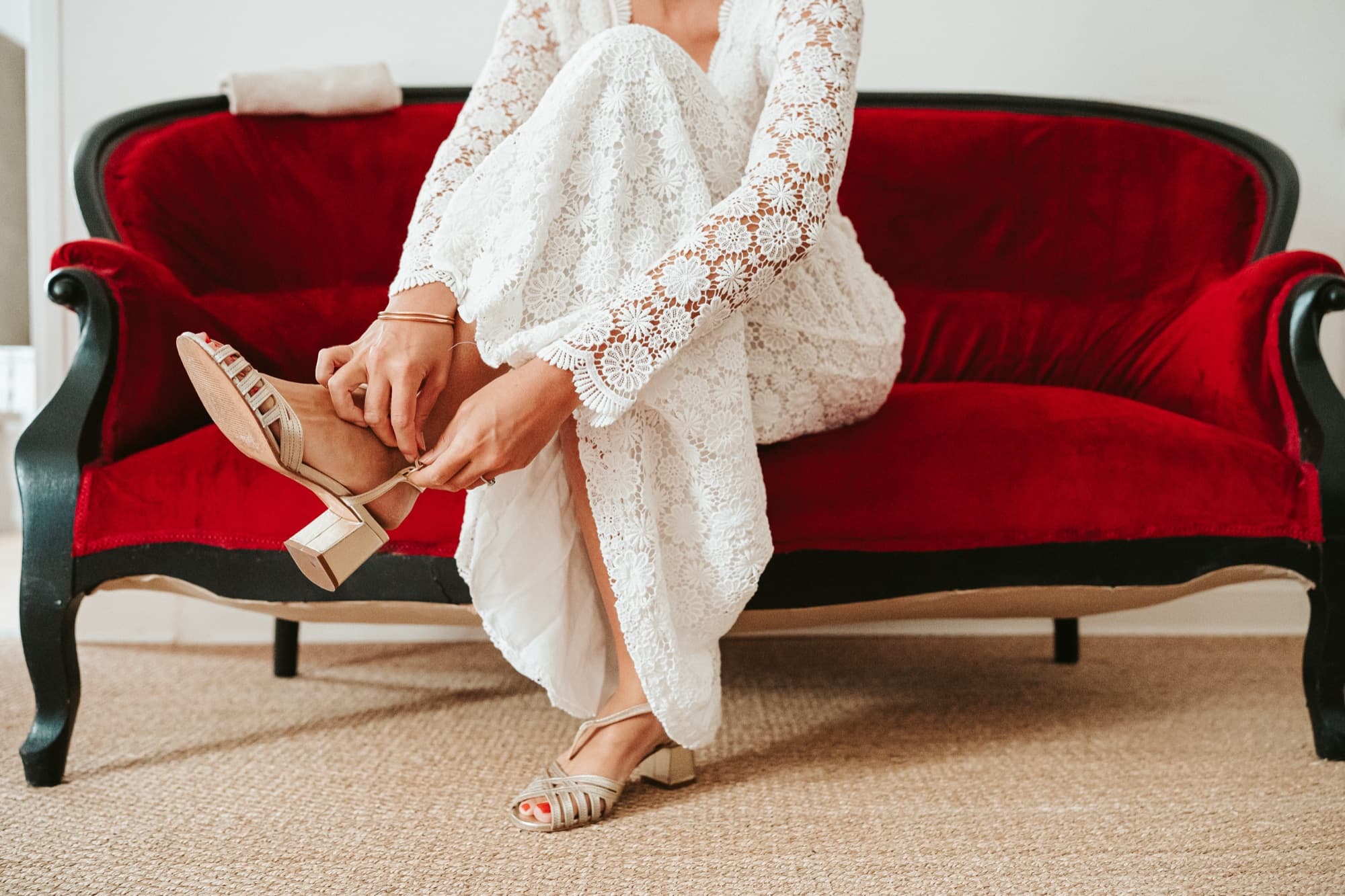 Femme en robe blanche sur un canapé de velours rouge